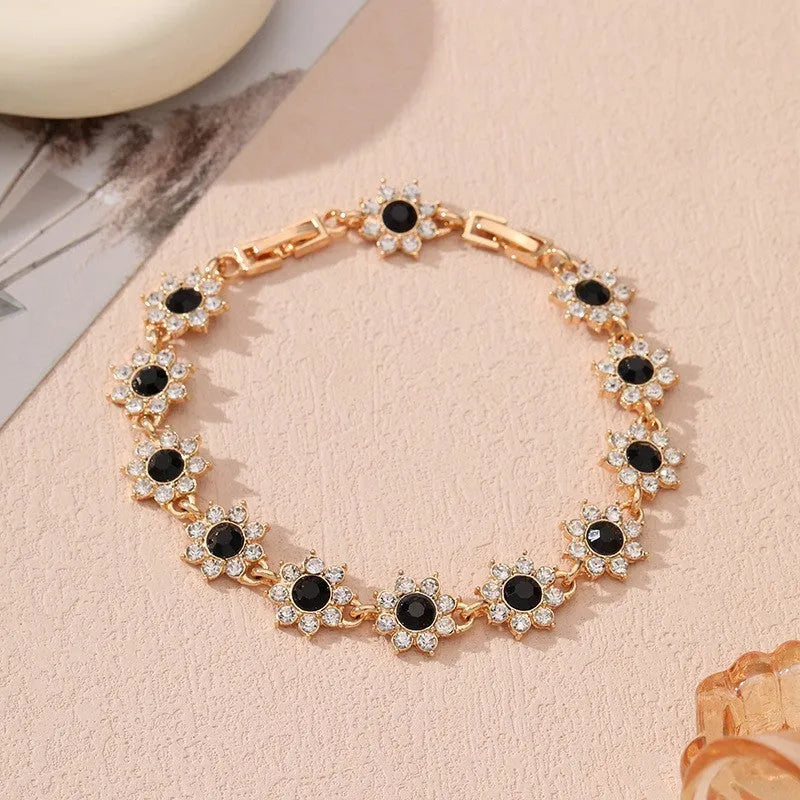 A gold or silver electroplated zinc alloy flower bracelet with coloured gems.