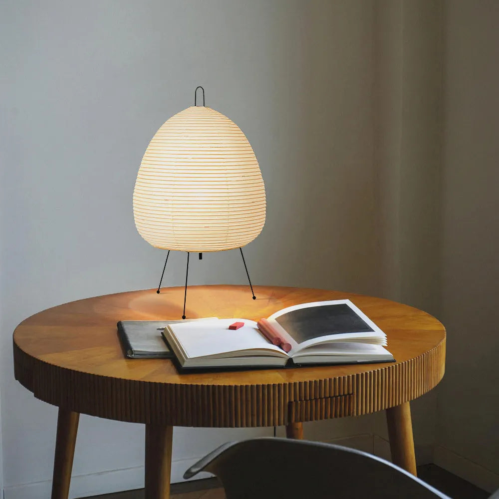 Japanese style handmade rice paper lantern table lamp with aluminium base on a wooden table.