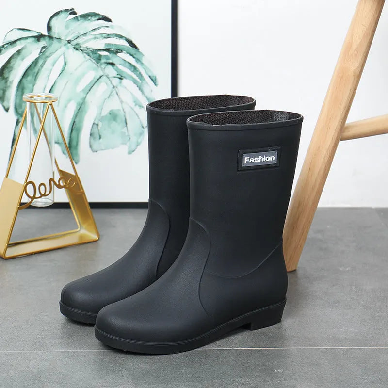 Women's mid-calf PVC rain boot in black on a wet surface.