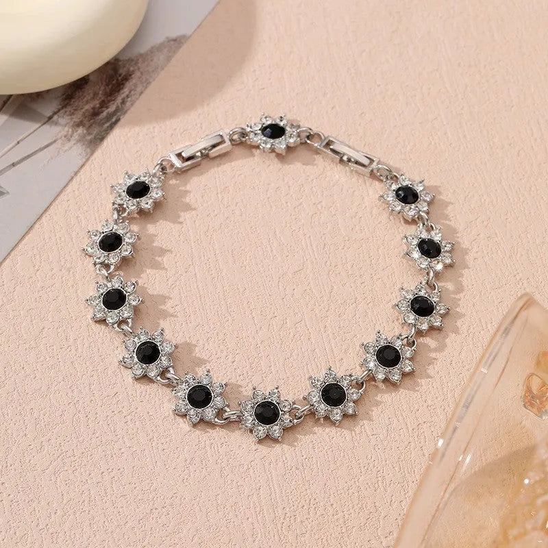 A gold or silver electroplated zinc alloy flower bracelet with coloured gems.