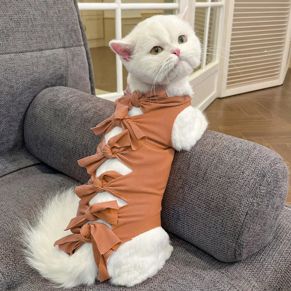 Cat wearing a pink lace-up polyester sterilisation suit after surgery, showing the adjustable tie closure.