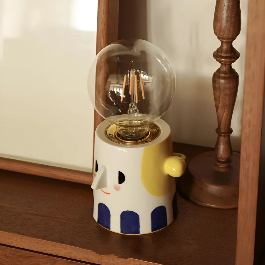 Handmade ceramic table lamp with a ball-shaped headlight on a neutral background.
