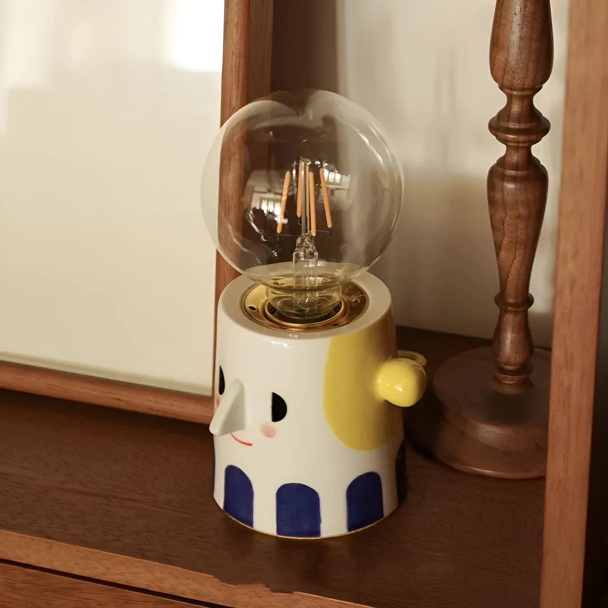 Handmade ceramic table lamp with a ball-shaped headlight on a neutral background.
