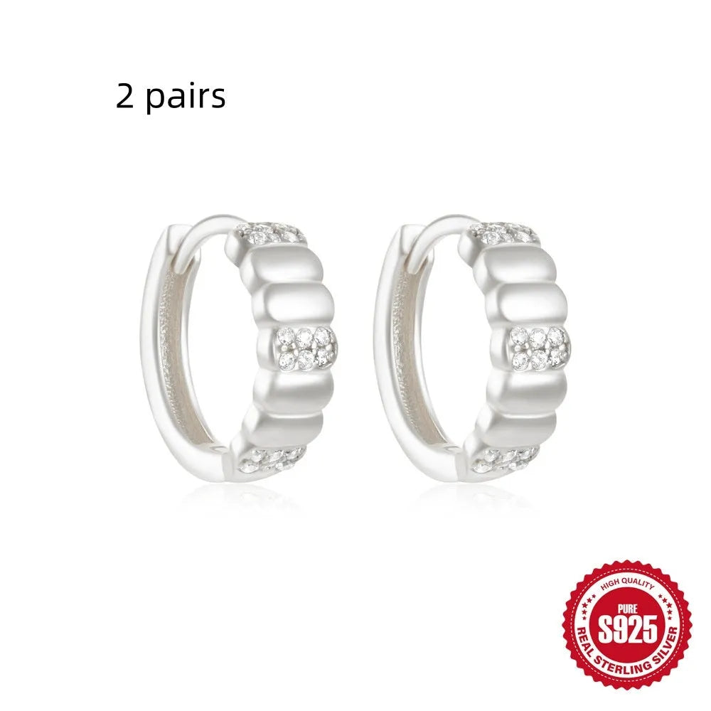 Sterling silver geometric stud earrings with a small round shape and classic diamond detail on a white background.