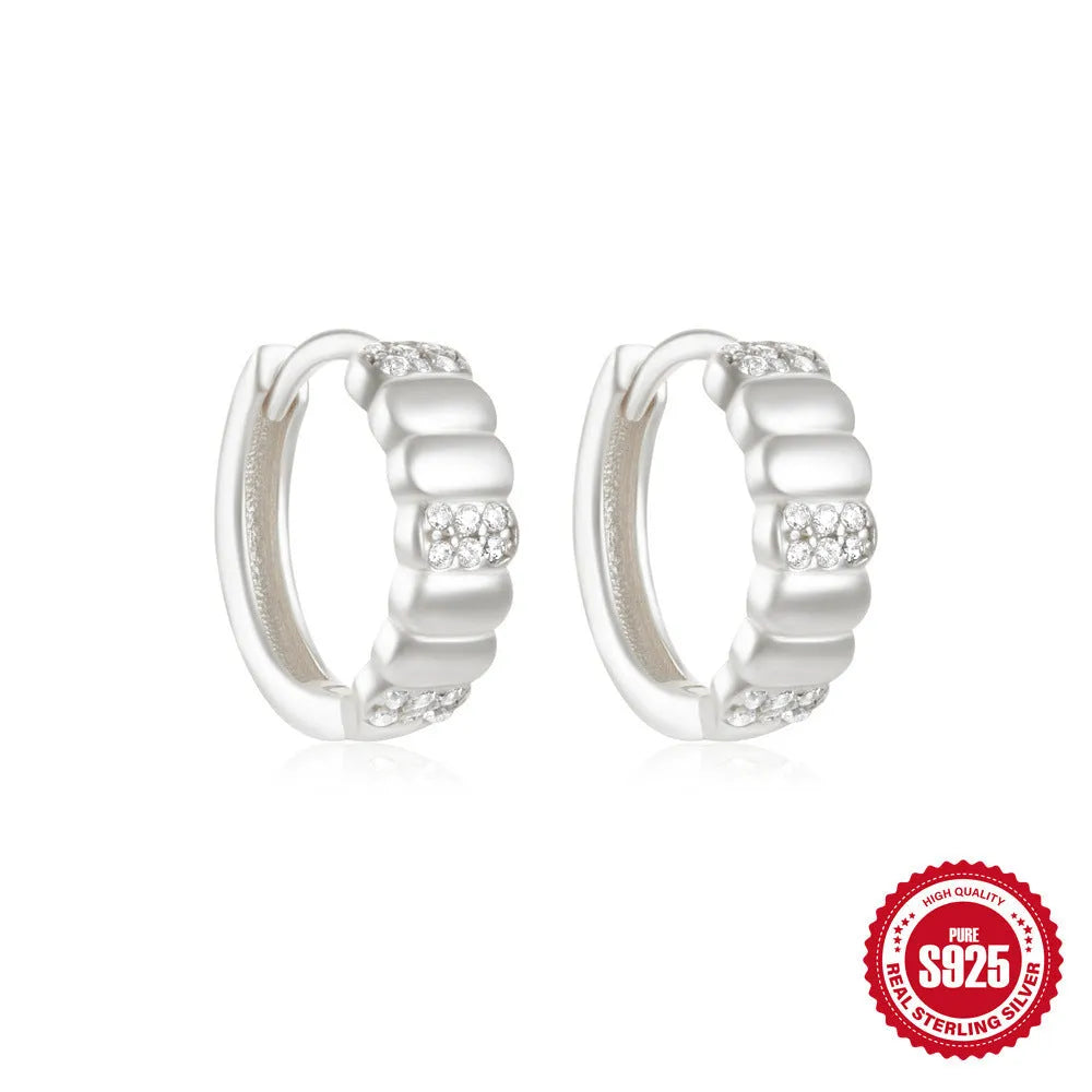 Sterling silver geometric stud earrings with a small round shape and classic diamond detail on a white background.