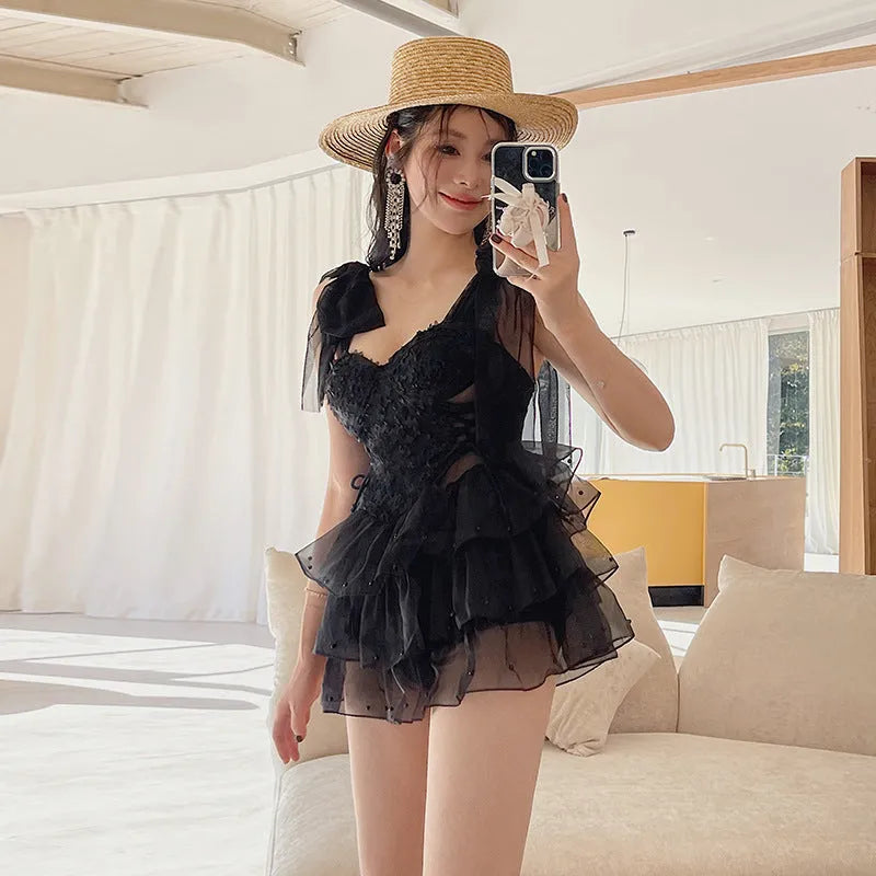 Black conservative one-piece swimsuit with gathered chest and full belly coverage.