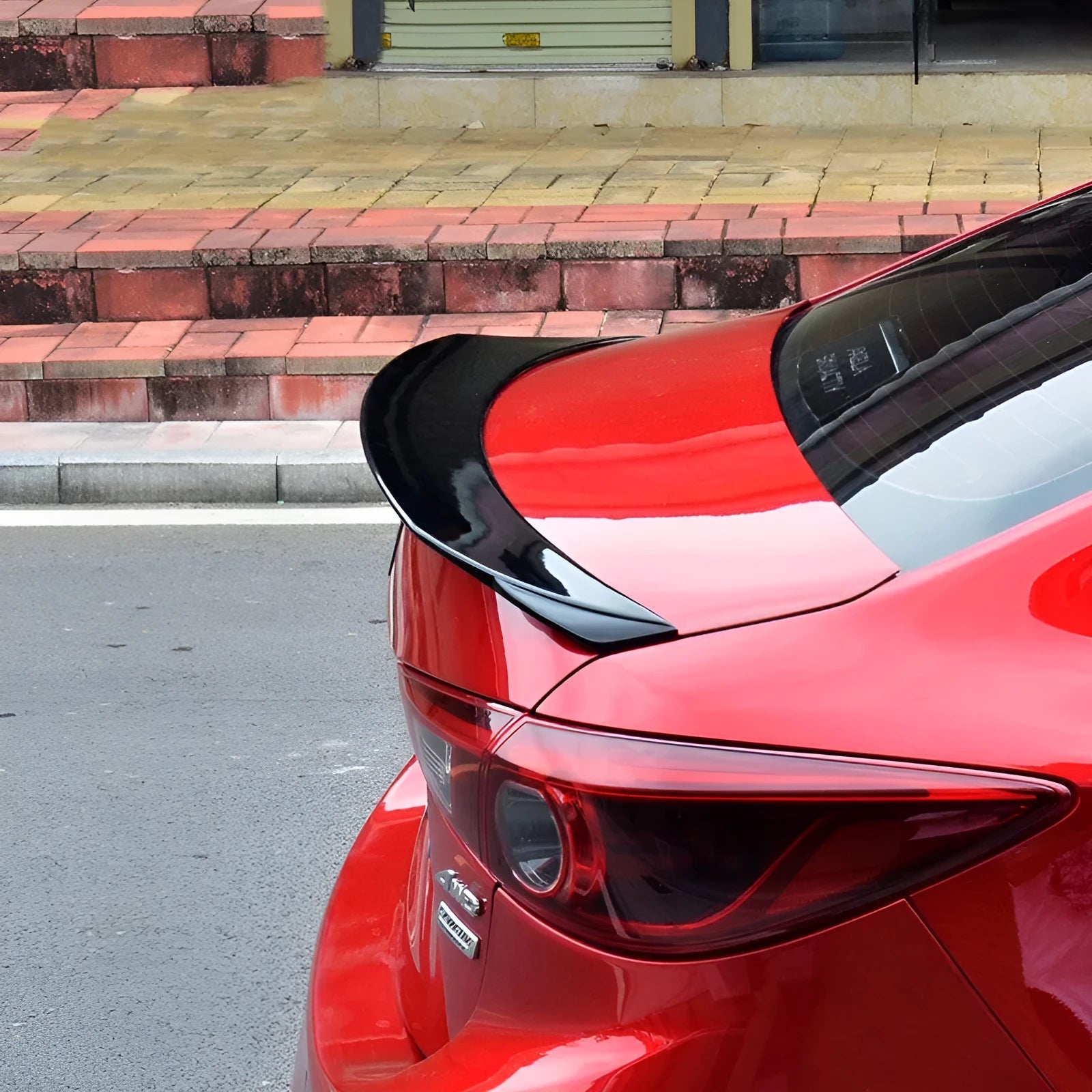Mazda 3 Axela Exela rear diffuser spoiler tail trim in bright black installed on car bumper.