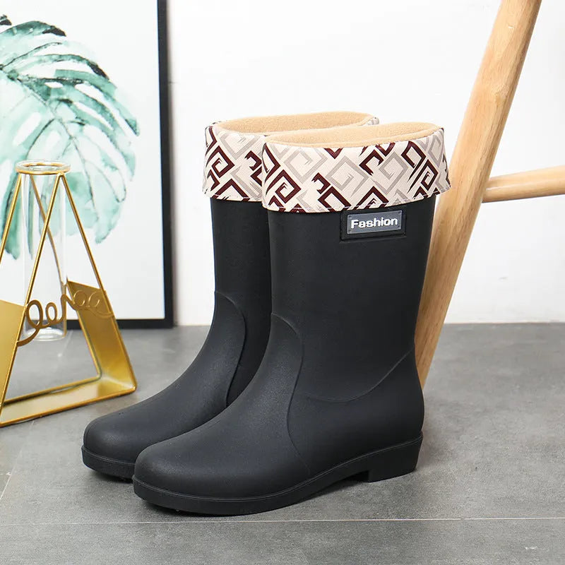 Women's mid-calf PVC rain boot in black on a wet surface.