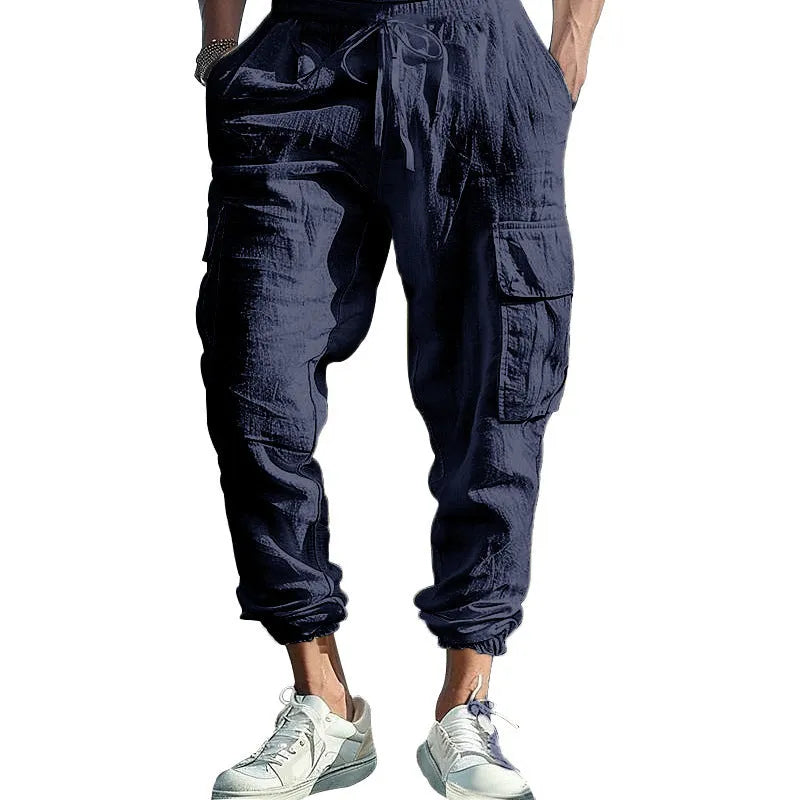 Man wearing loose, ankle-tied linen trousers in a solid colour with visible pockets.