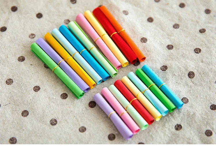 Colourful assortment of small paper scrolls with metal eyelets for drift bottle messages.