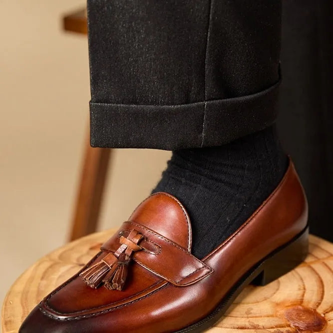 Men's black and brown tassel loafers with polished leather uppers and rubber soles