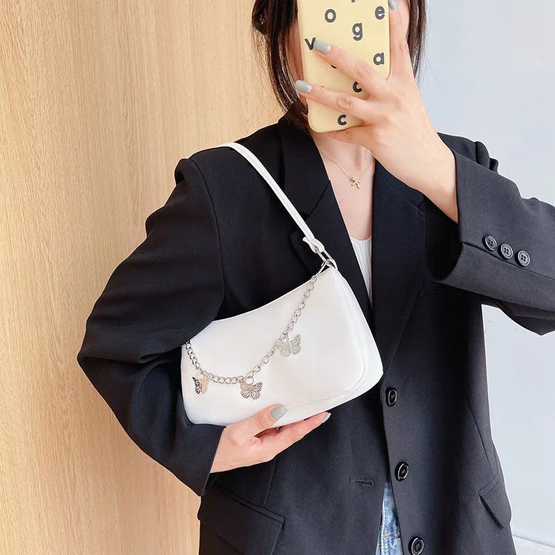 Retro-style square crossbody handbag with a butterfly clasp on its chain strap.