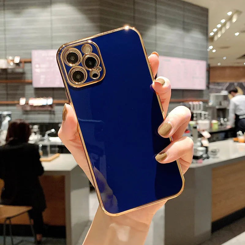 Gold plated iPhone case with silicone stripes for iPhone 13 and 14 models on a table.