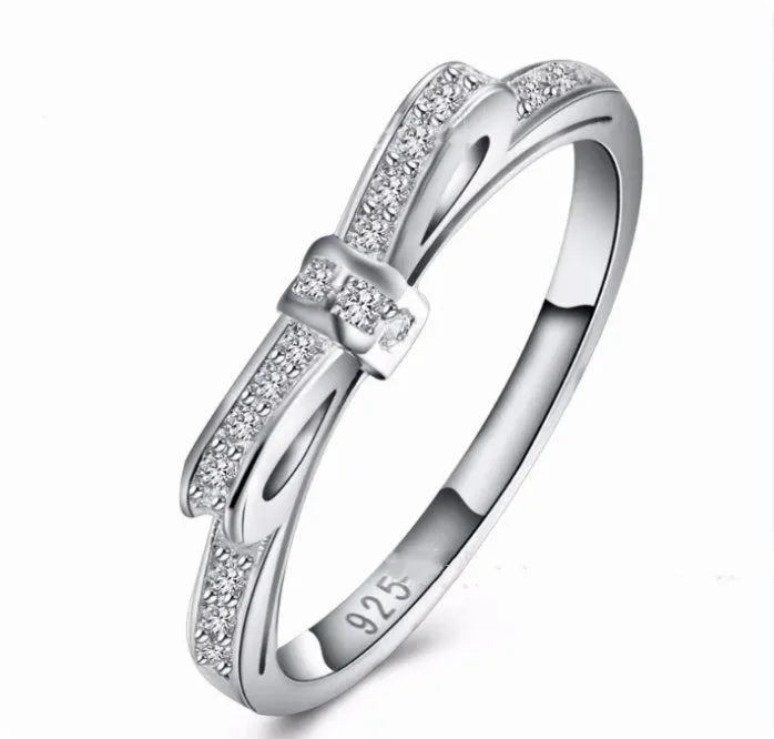 Silver bow-shaped rhinestone ring with zircon crystals on finger