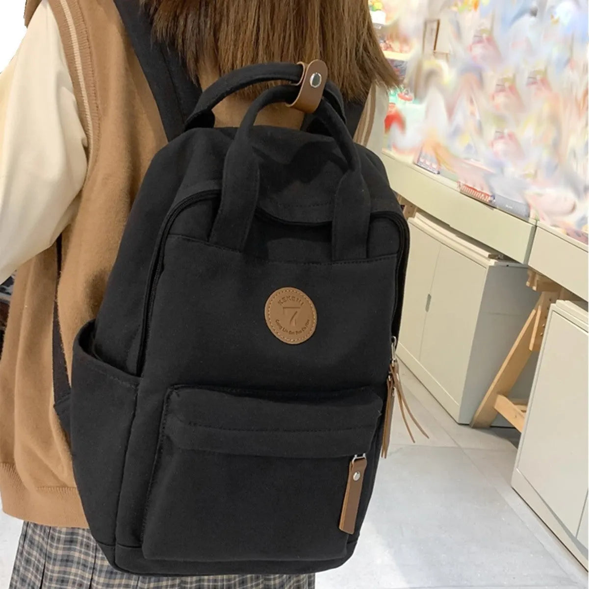 Black Oxford cloth fashion backpack with curved shoulder straps showing retro sewing thread details