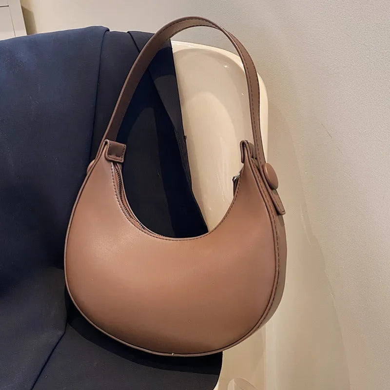Women's retro brown dumpling-shaped PU shoulder bag showing front pocket and crossbody strap.