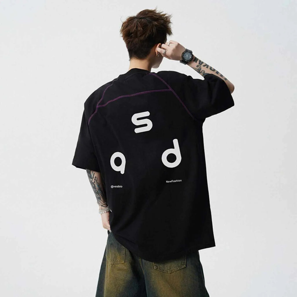 Man wearing a black loose-fit cotton T-shirt with a letter print on the chest.