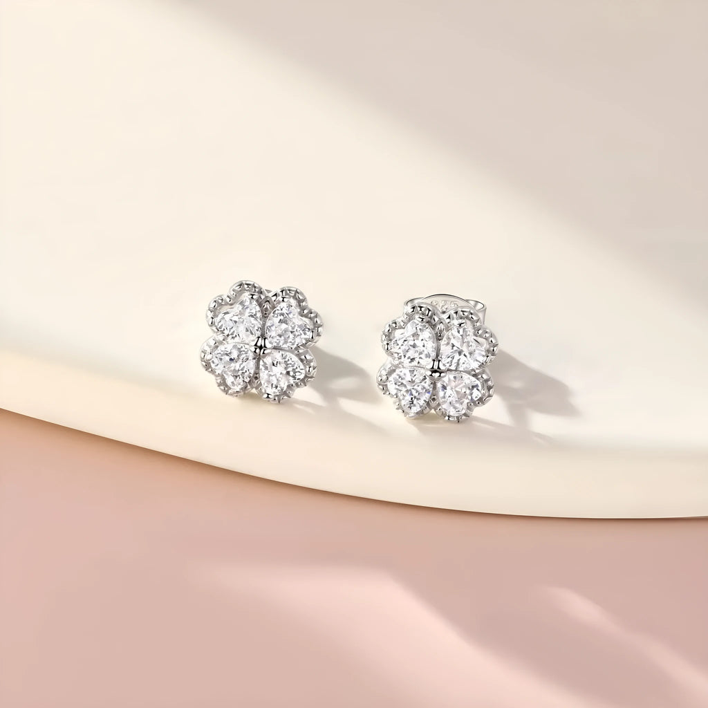 Close-up of women's 925 silver earrings with a four-leaf clover and heart design, inlaid with zircon stones in white gold colour.
