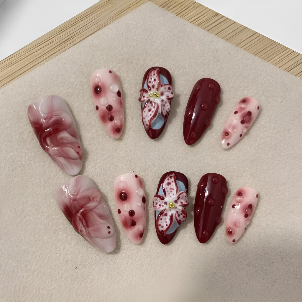 False nails set with three-dimensional hand-painted rose, tulip, shell, bow, and leopard print designs in almond colour