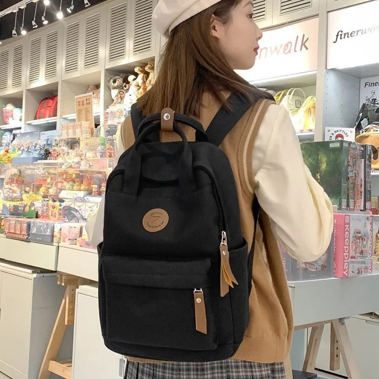 Black Oxford cloth fashion backpack with curved shoulder straps showing retro sewing thread details