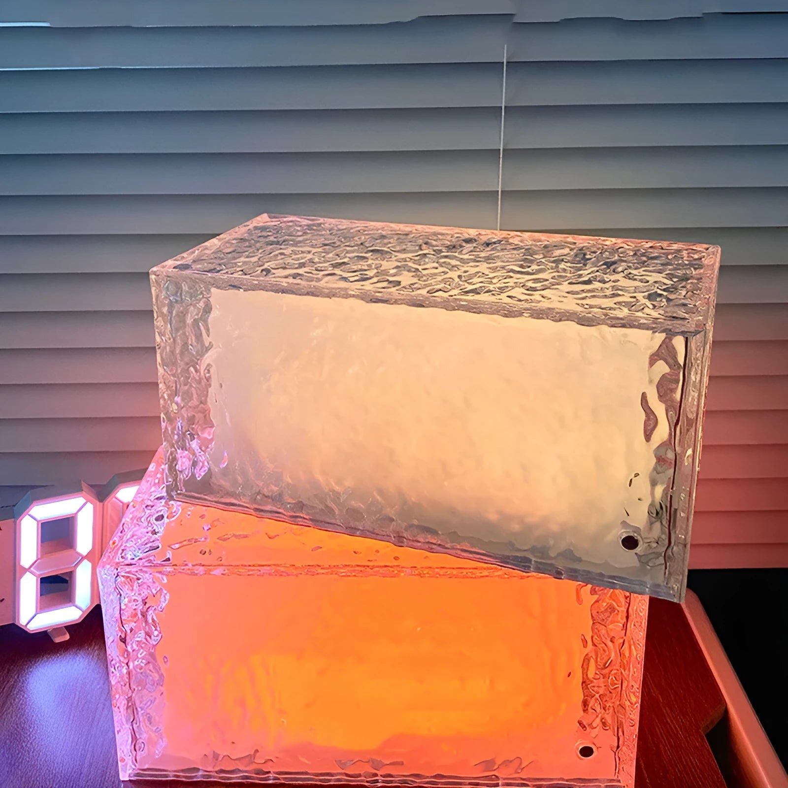 Clear geometric ice cube-shaped night lamp with multi-colour LED glow on a desk.