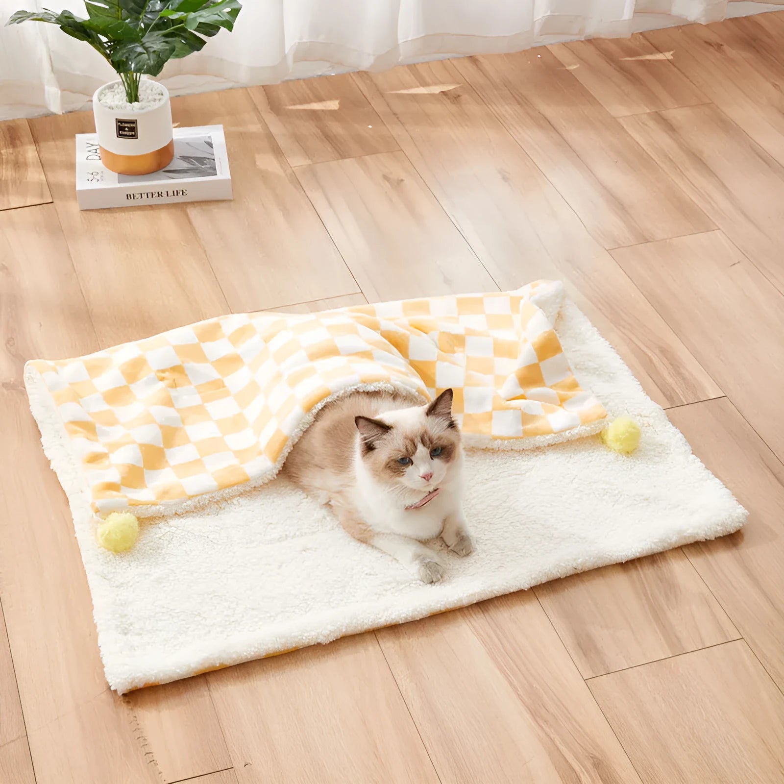 Green plaid pattern pet blanket with fur ball decoration on a sofa.
