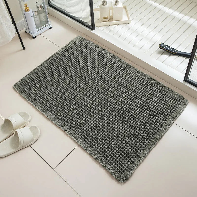 Square checkered-pattern non-slip bathroom carpet in a neutral colour on tiled floor.