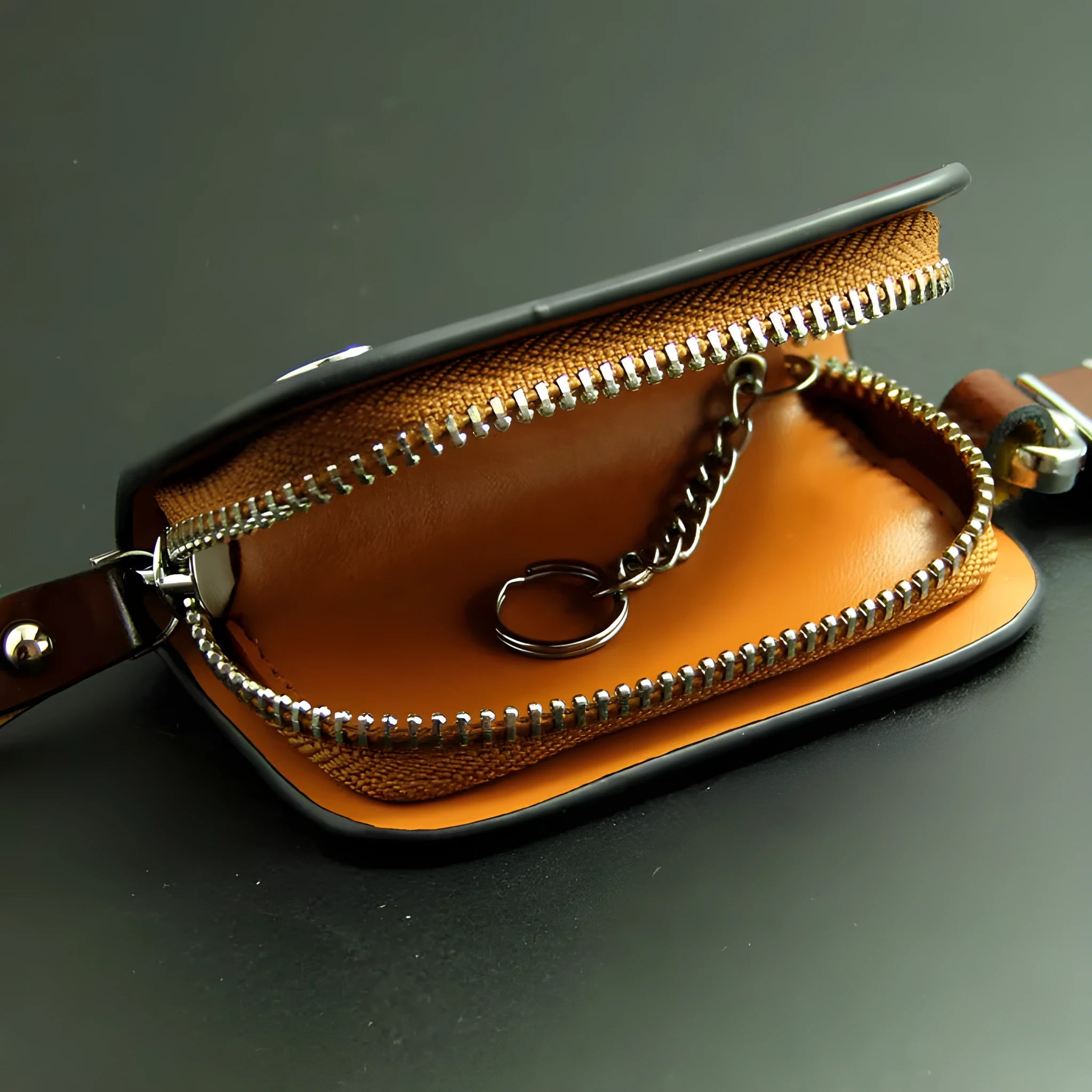 Black frosted leather car key case with zipper, next to a car key