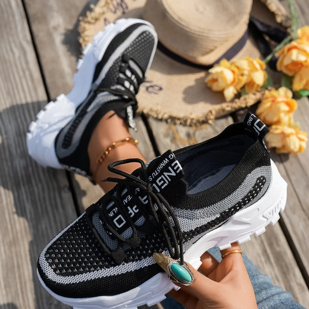 Women's Flyknit mesh lace-up sneakers in a grey colourway on a flat rubber sole.