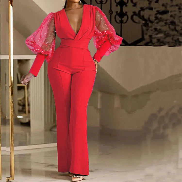 Red women's jumpsuit with mesh stitching on the torso, long sleeves, elastic waist, and wide-leg trousers.