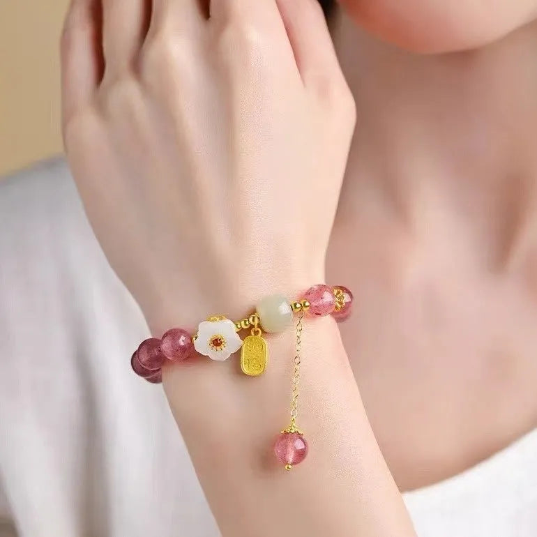 Handcrafted strawberry quartz crystal bracelet with peach blossom design on wrist
