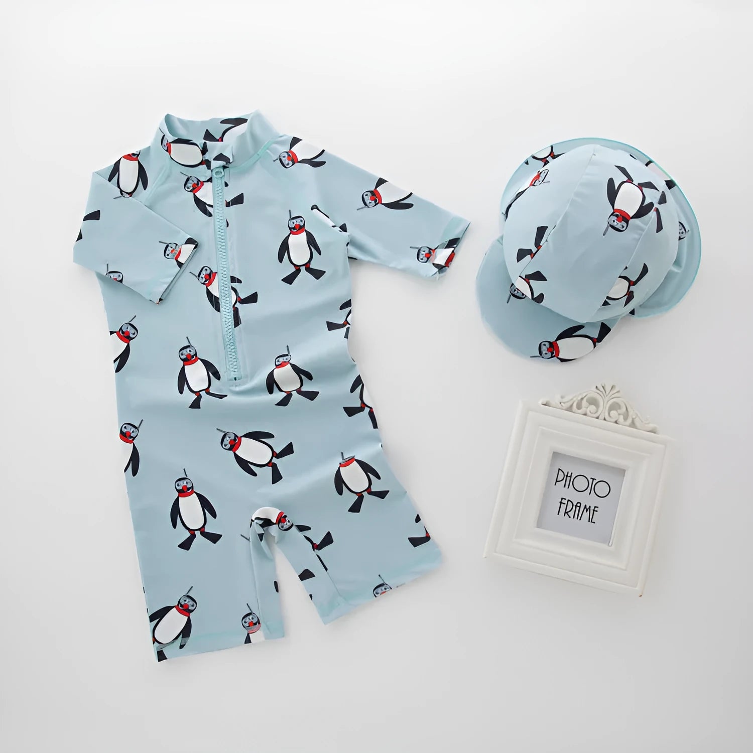 Boys' penguin print long sleeve swim top and matching swimming cap set on a hanger.