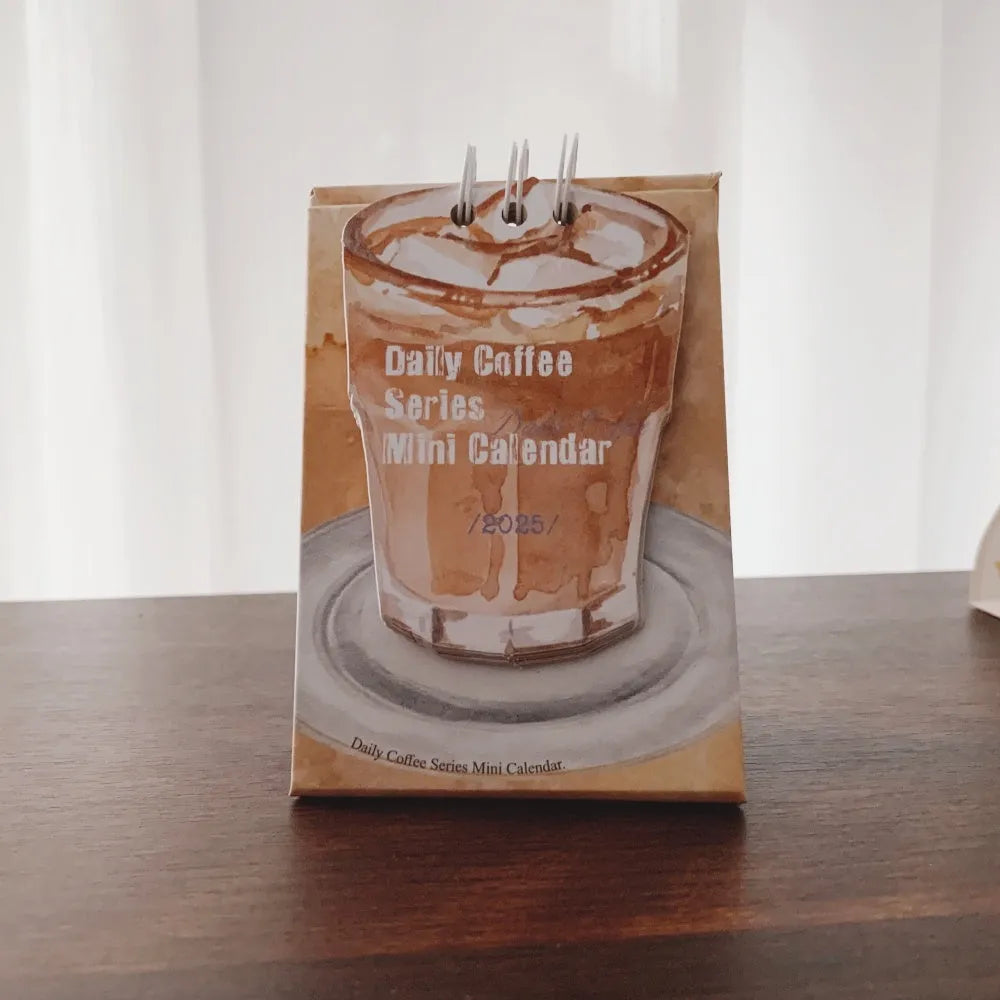 Mini A6 paper desk calendar for 2025 open to a monthly page with coffee-themed design.