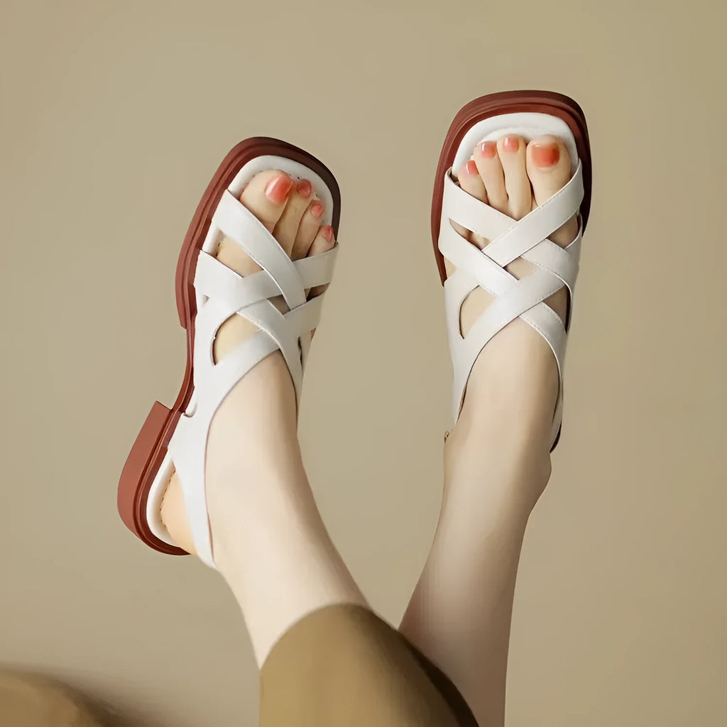 Women's black patent leather low heel sandals with square toe and cross ankle strap.