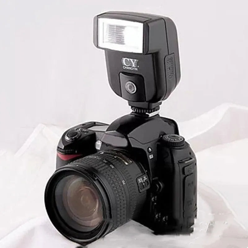 Compact black SLR camera flash unit shown tilted upwards on a hotshoe, illustrating its 90-degree bounce flash capability.