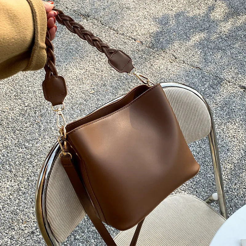 Khaki PU leather crossbody bucket bag with weaving texture and single shoulder strap.