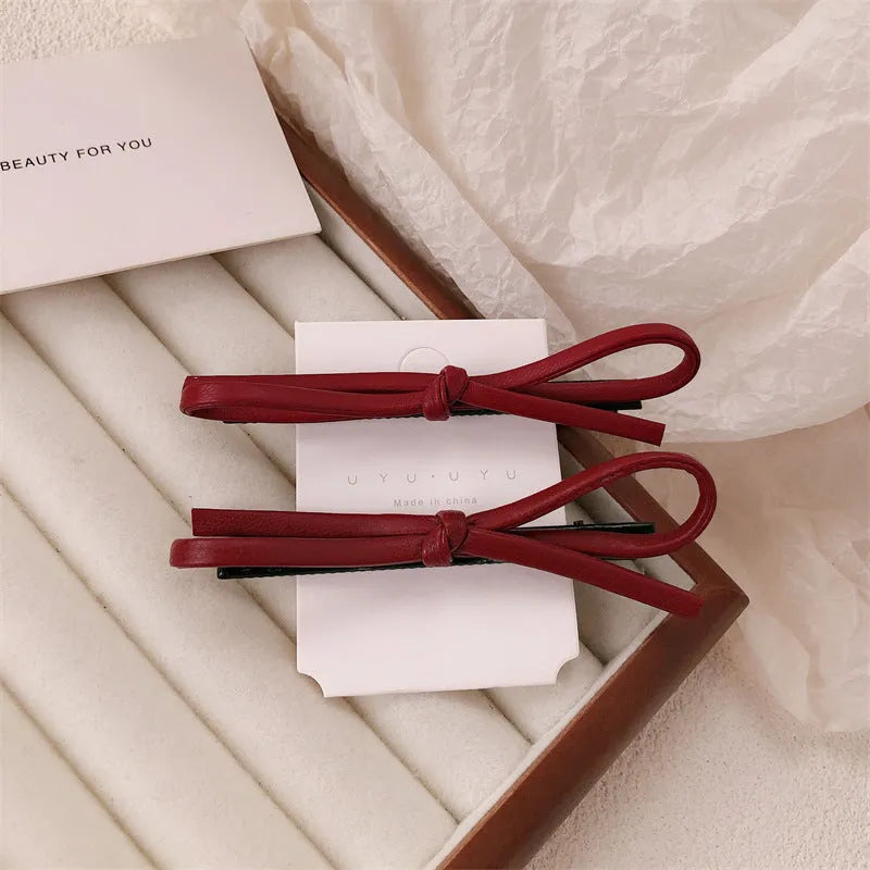 Wine red leather bow barrette hair clip on a white background.