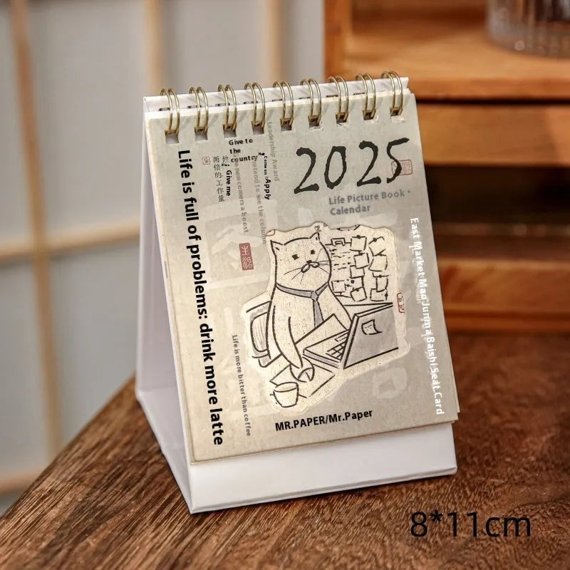Mini A6 paper desk calendar for 2025 open to a monthly page with coffee-themed design.
