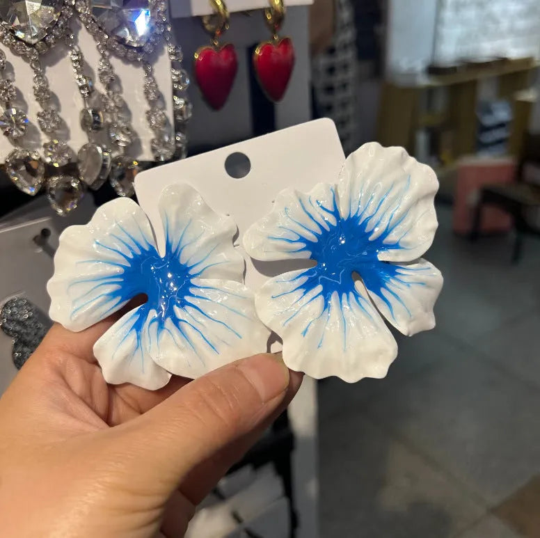 Close-up of alloy floral stud earrings with oil-spot glaze in blue, green, purple, and rose colour options.