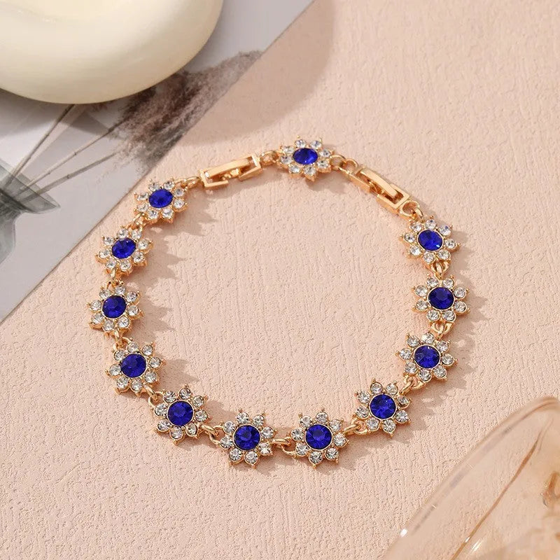 A gold or silver electroplated zinc alloy flower bracelet with coloured gems.