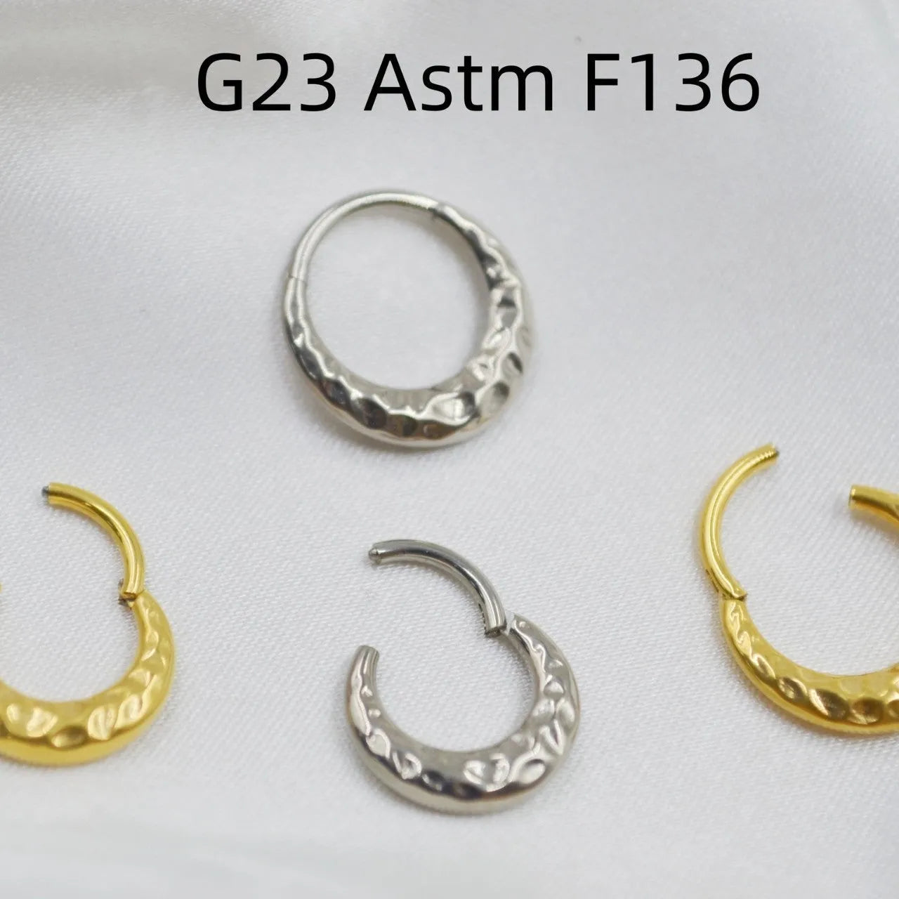 Close-up of a titanium alloy concave-convex nose ring in gold finish, showing carved detail and ring shape.