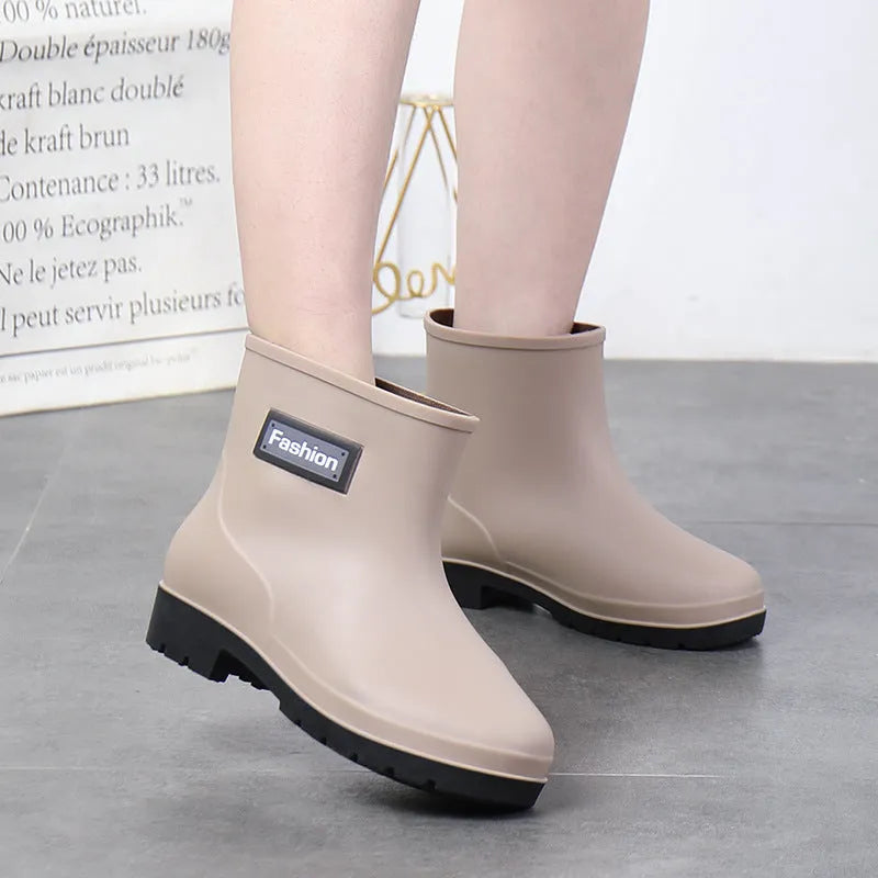 Women's mid-calf PVC rain boot in black on a wet surface.