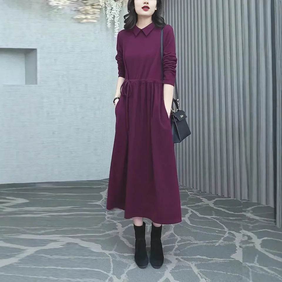 Purplish red plus size women's dress with long skirt and extra-long sleeves on a model.