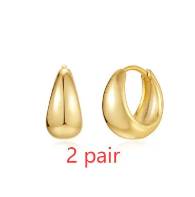 A pair of simple geometric brass earclip earrings with a round element and electroplated golden finish.
