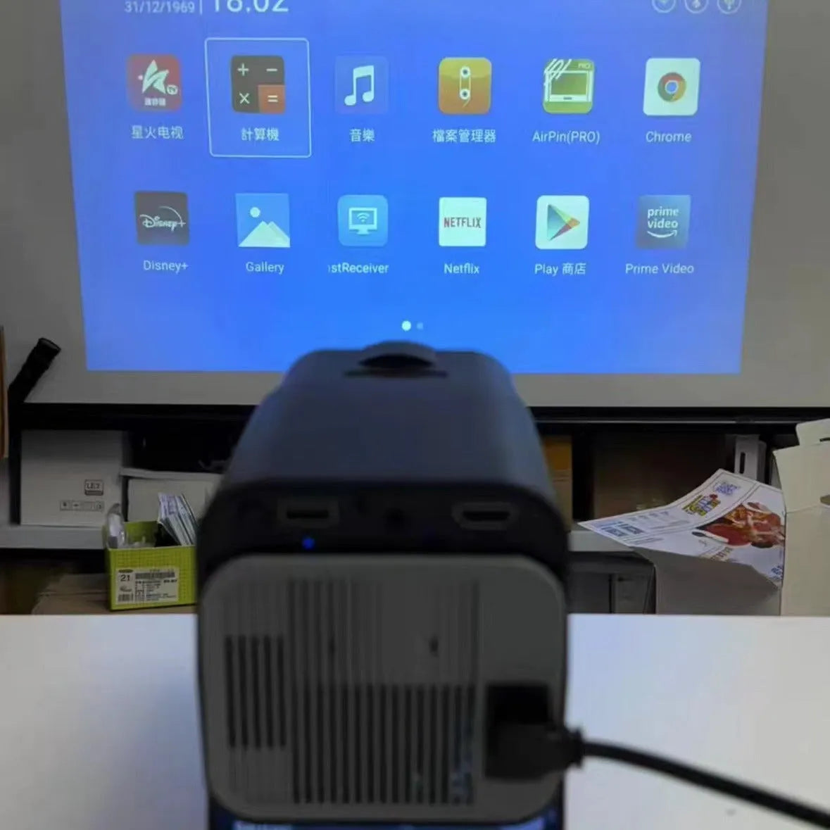 A white HD wireless game projector for home use on a wooden surface.