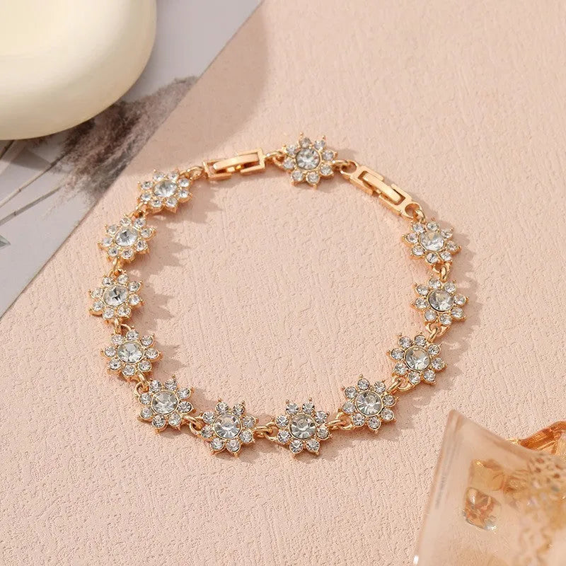 A gold or silver electroplated zinc alloy flower bracelet with coloured gems.