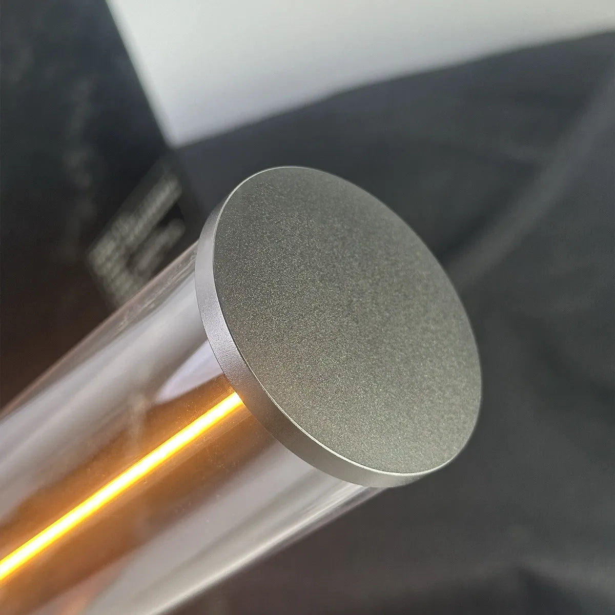 Glass cylindrical LED night light with magnetic base on a metal surface, showing USB charging port.