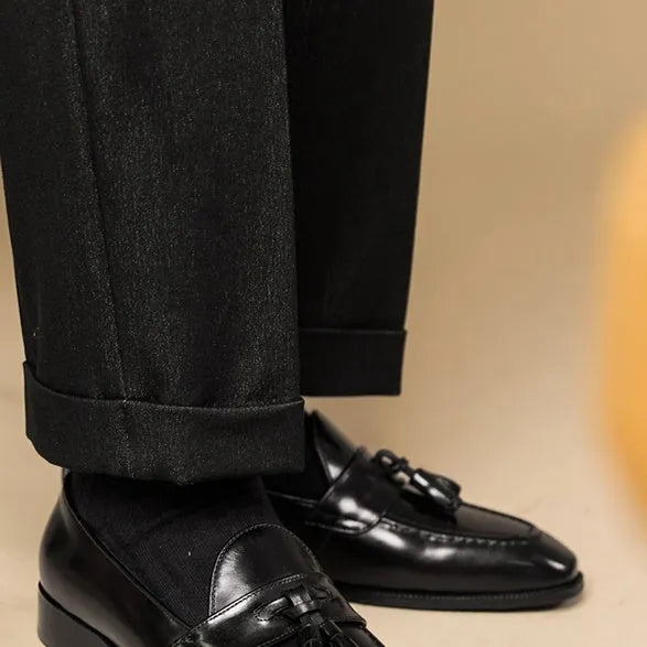 Men's black and brown tassel loafers with polished leather uppers and rubber soles