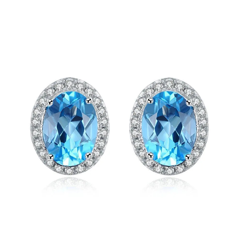 Four-piece 925 Sterling Silver geometric jewellery set with blue topaz gems, showing earrings, ring, pendant, and necklace.