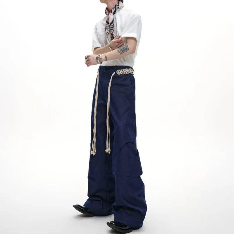 Man wearing dark blue straight-leg cotton jeans with heavy waistband stitching and decorative pocket details